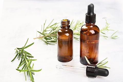 Aromatherapie Symbolbild: Rosmarinzweige und Braunfläschchen