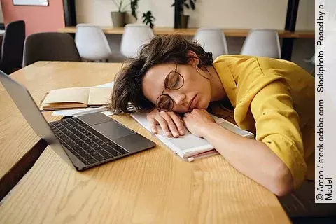 Frau mit geschlossenen Augen am Schreibtisch