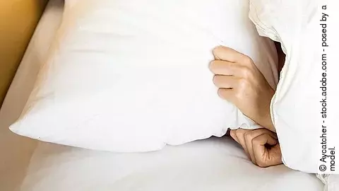 Mensch im Bett mit der Decke über dem Kopf