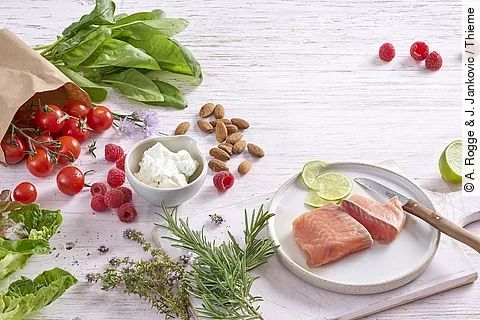 Mandeln, Lachs, Limette, Tomaten, Himbeeren, Spinat, Rosmarin, Thymian auf weißem Holzuntergrund