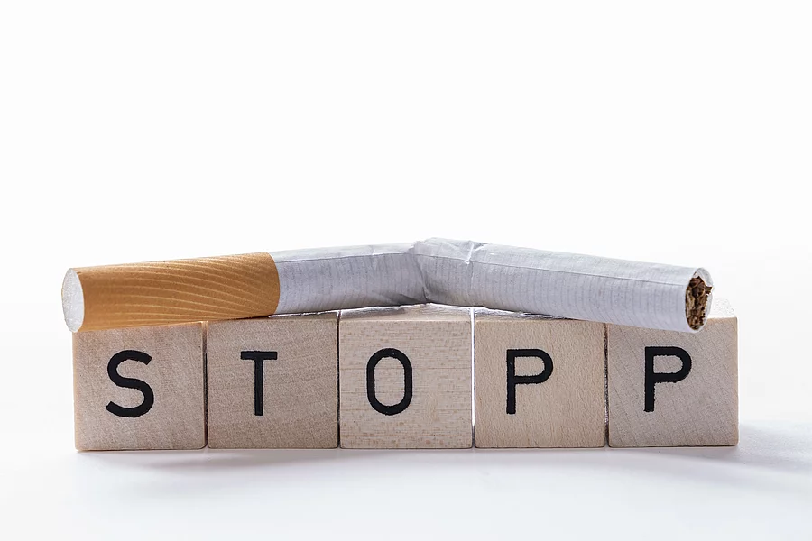 5 Holzklötze mit den Buchstaben STOPP, darauf liegt eine zerbrochene Zigarette