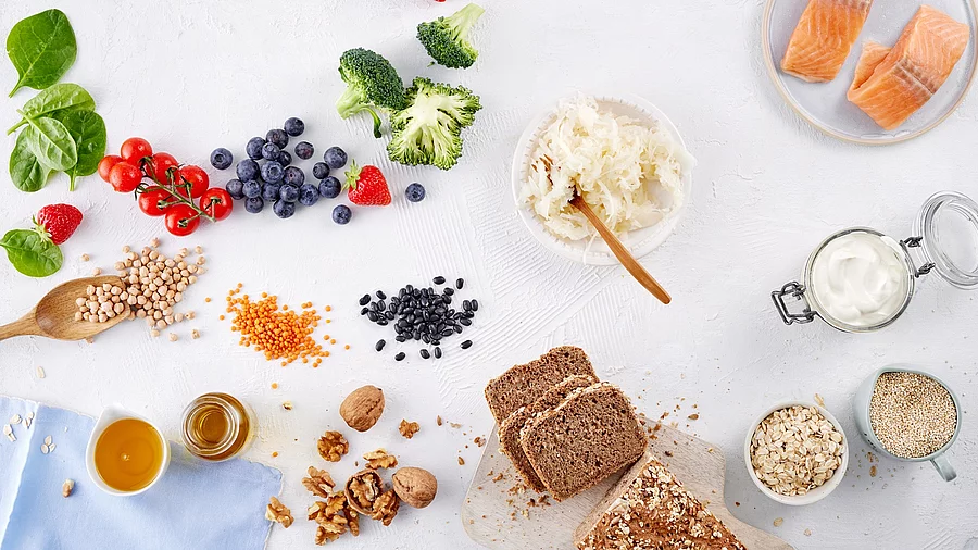 Tableau mit gesunden Lebensmitteln: Beeren, Broccoli, Haferflocken, Walnüsse, Lachs, Vollkornbrot, Linsen