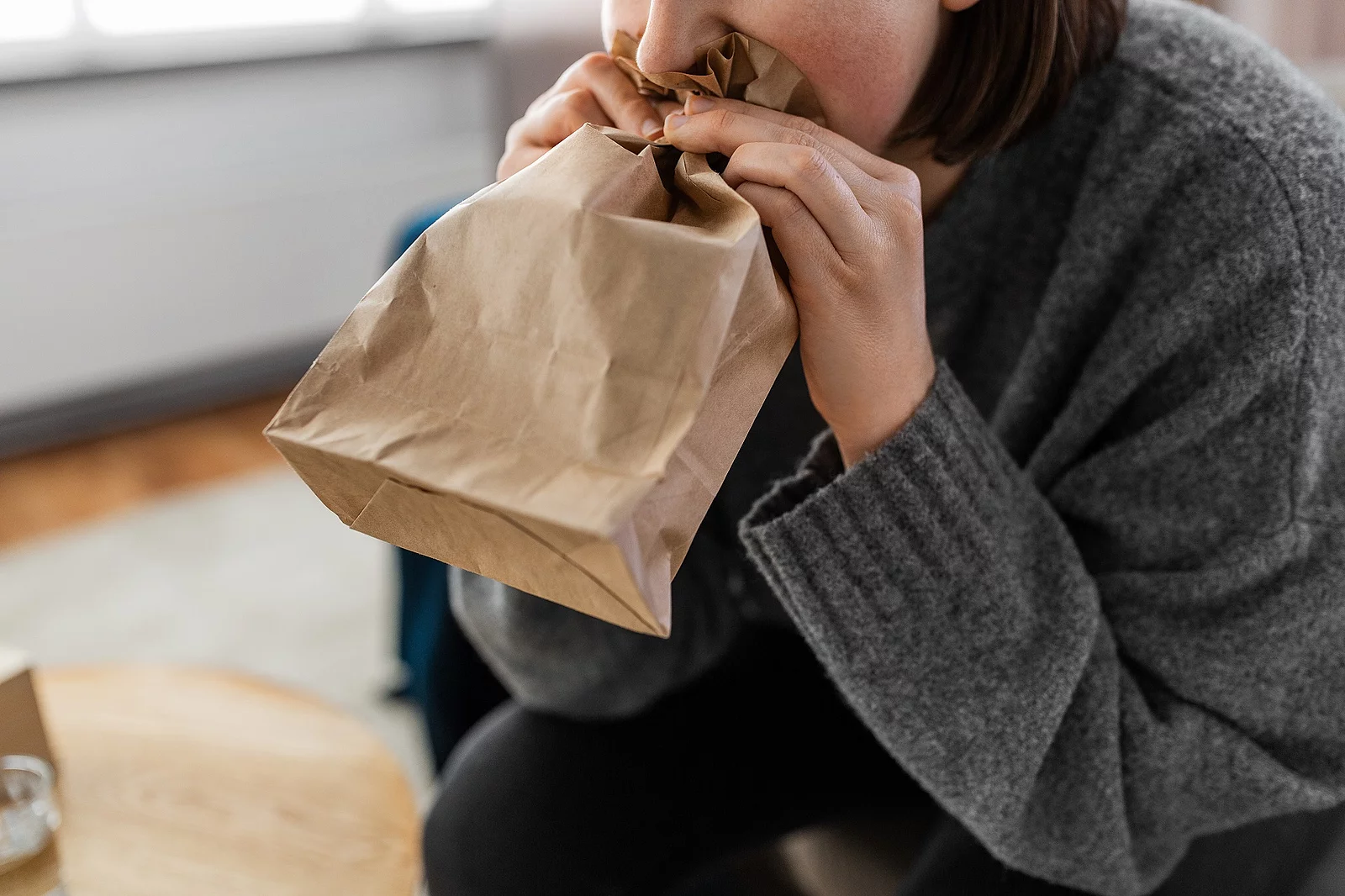 mental health and psychological problem concept - close up of woman having panic attack breathing to bag at home mental health and psychological problem concept - close up of woman having panic attack breathing to bag at home