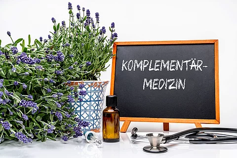 Schreibtisch mit Lavendel, Stethoskop und eine Tafel mit der Aufschrift Komplementärmedizin