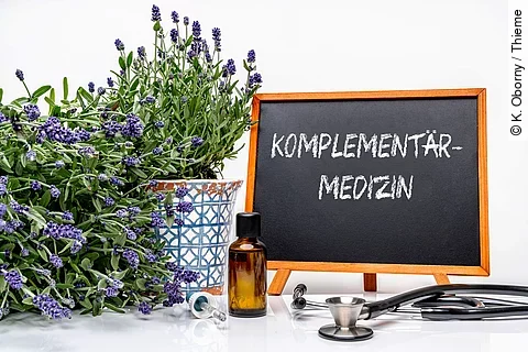Schreibtisch mit Lavendel, Stethoskop und eine Tafel mit der Aufschrift Komplementärmedizin