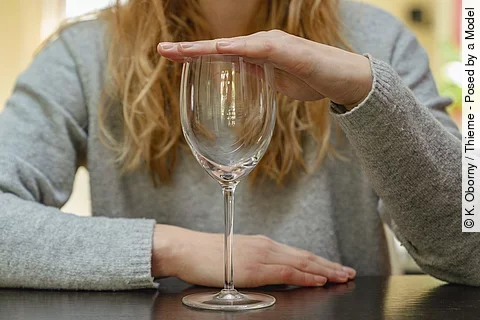 Junge Frau hält die Hand über ein leeres Weinglas