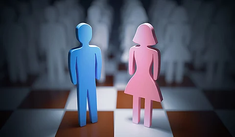 rosa weibliche Holzfigur und blaue männliche Holzfigur auf einem Schachbrett