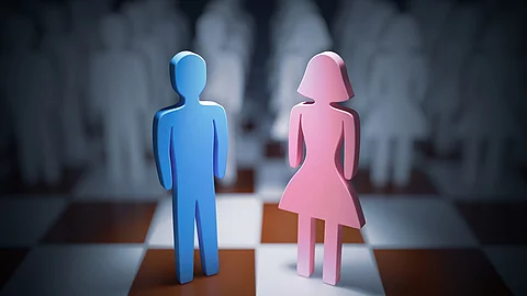 rosa weibliche Holzfigur und blaue männliche Holzfigur auf einem Schachbrett