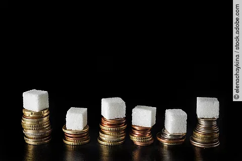 Zuckerwürfel auf Geldmünzen gestapelt.