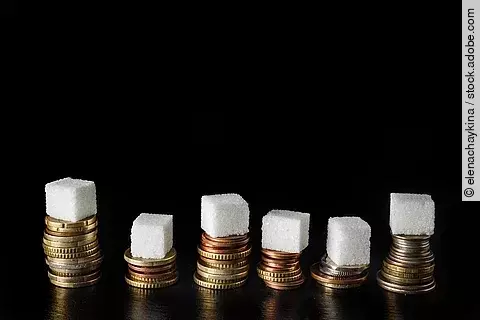 Zuckerwürfel auf Geldmünzen gestapelt.