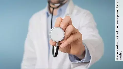 Arzt hält ein Stethoskop in die Kameralinse