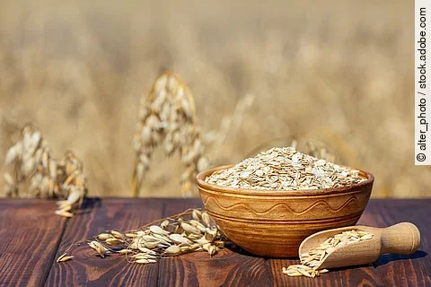 Haferflocken in Holzschale, daneben Haferrispe