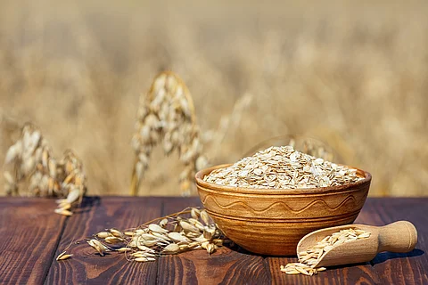 oat flakes and field Haferflocken in Holzschale, daneben Haferrispe