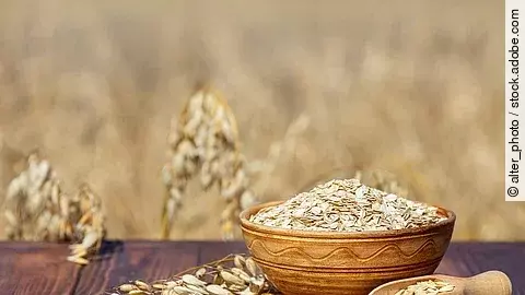 Haferflocken in Holzschale, daneben Haferrispe