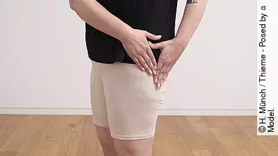 Stehende Frau streicht mit den Händen ihre Hüfte aus