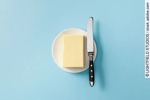 Aufsicht auf ein Stück Butter mit einem Buttermesser daneben