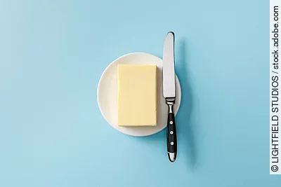 Aufsicht auf ein Stück Butter mit einem Buttermesser daneben