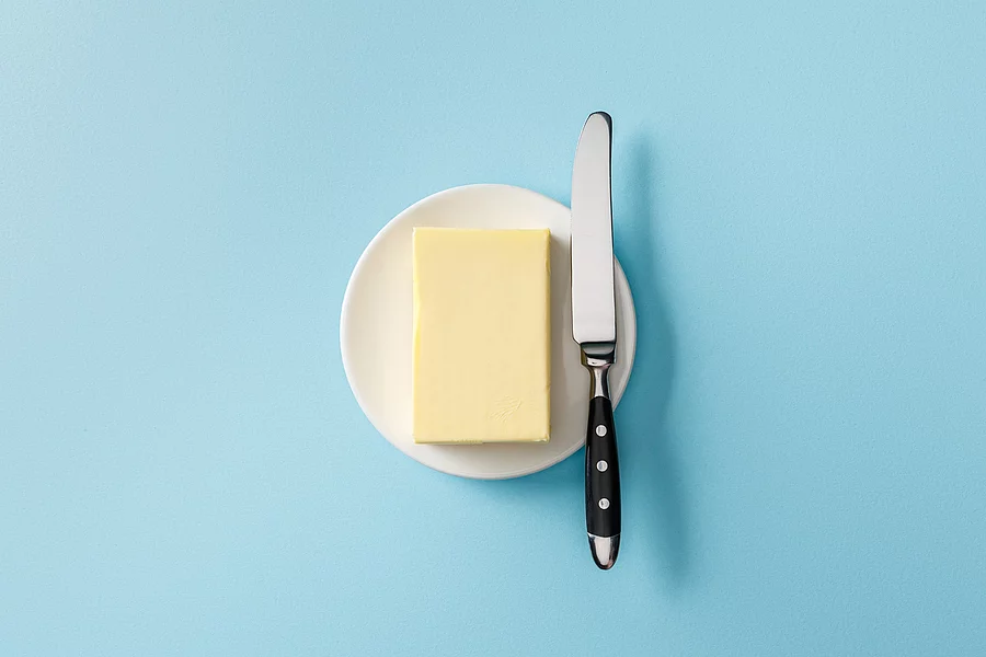 Aufsicht auf ein Stück Butter mit einem Buttermesser daneben