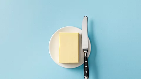 Aufsicht auf ein Stück Butter mit einem Buttermesser daneben