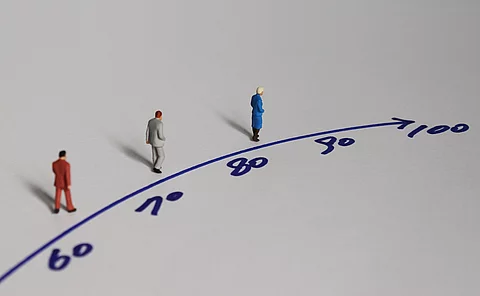 Illustration: 3 Menschen laufen auf einer Linie mit Zahlen zwischen 60 und dem Ziel 100 Jahre