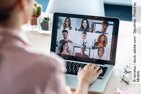Frau sitzt vor dem Laptop in einem Online Meeting.