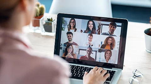 Frau sitzt vor dem Laptop in einem Online Meeting.