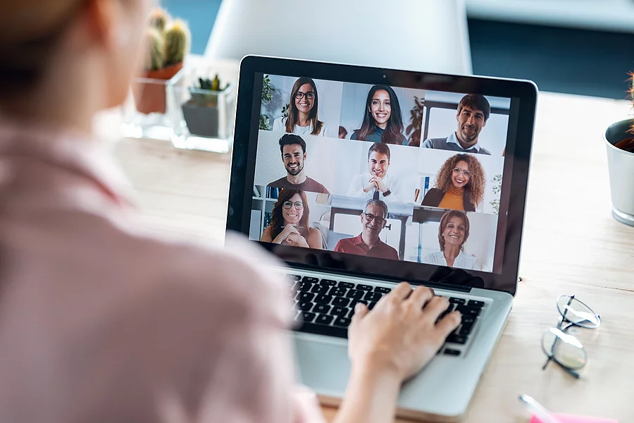 Frau sitzt vor dem Laptop in einem Online Meeting.