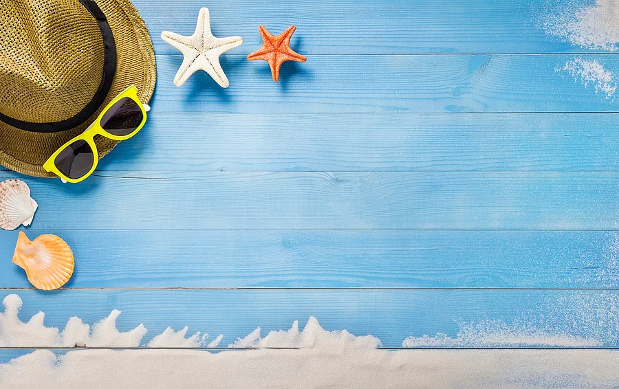 Sonnenhut, Sonnenbrille und Seesterne auf Holzunterlage