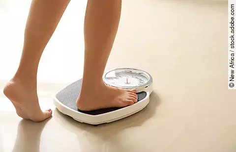 Eine Frau, die auf eine Waage steigt.