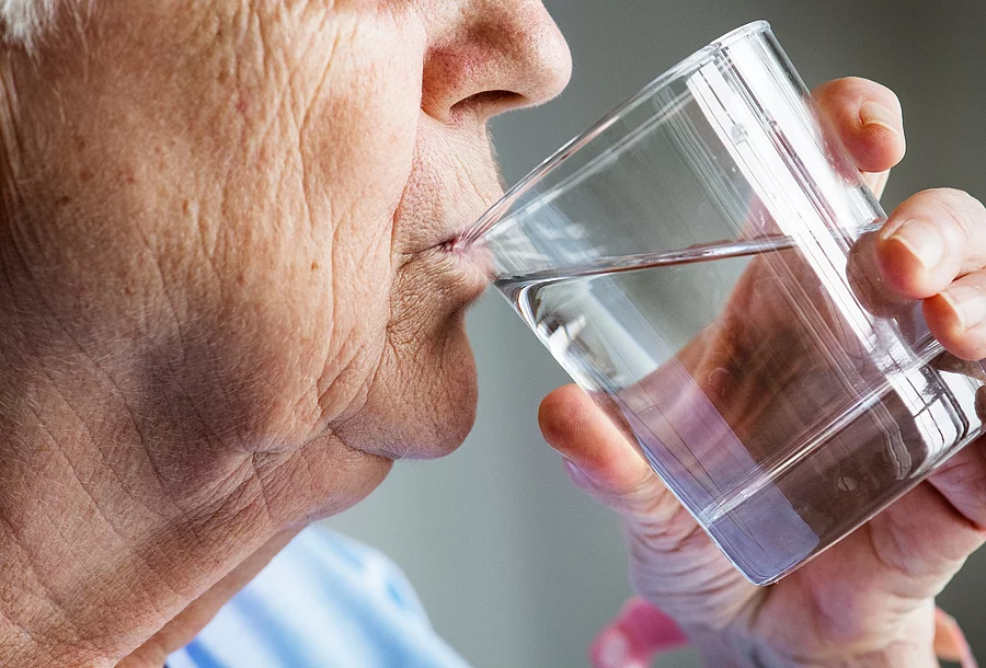 Side view of elderly woman drinking water alte Frau trinkt aus einem Wasserglas