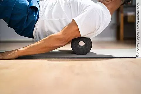 Mann macht eine Übung auf der Faszienrolle.