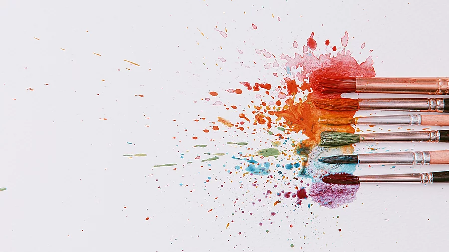 Pinsel und bunte Farbkleckse auf weißem Papier