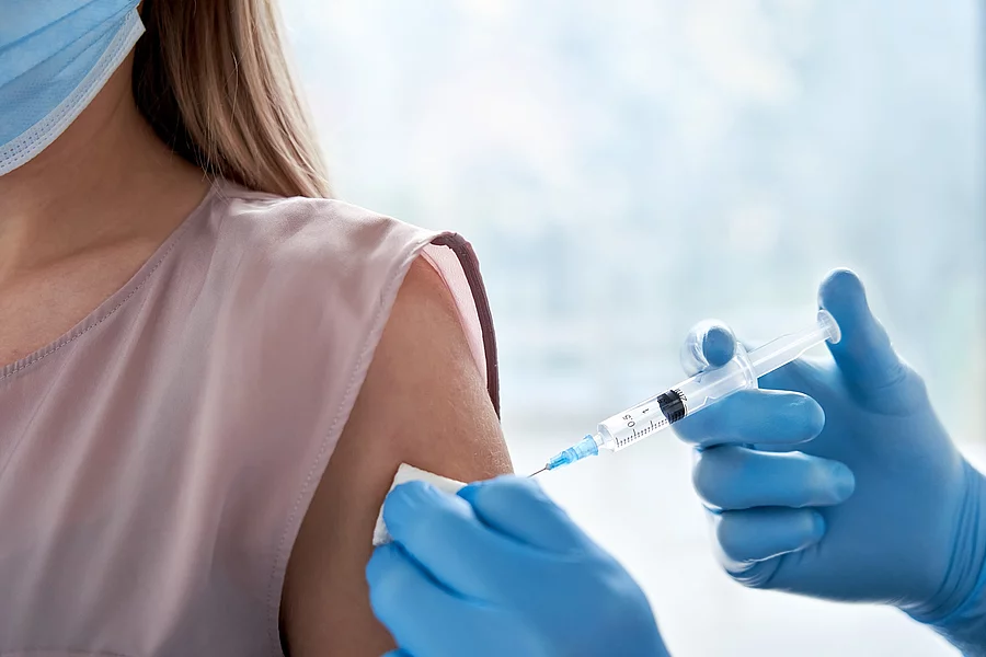 Patientin mit Maske, die eine Impfung erhält.