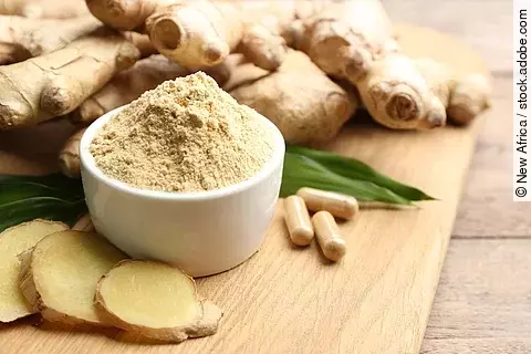Ingwerwurzel, Ingwerkapseln, Ingwerscheiben und Ingwerpulver auf einem Holzbrett