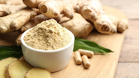 Ingwerwurzel, Ingwerkapseln, Ingwerscheiben und Ingwerpulver auf einem Holzbrett