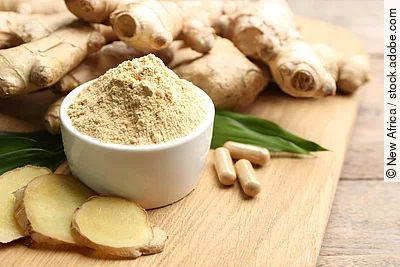 Ingwerwurzel, Ingwerkapseln, Ingwerscheiben und Ingwerpulver auf einem Holzbrett