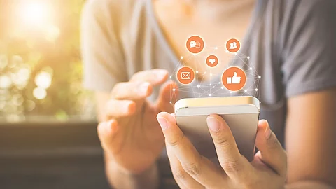 Frau benutzt ihr Smartphones, darüber sind verschiedene Icons abgebildet.