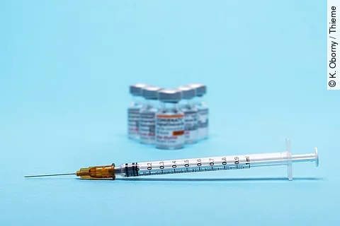 Spritze und Impfstoff-Ampullen auf blauem Hintergrund