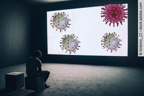 gebeugt sitzender Mann vor einer Leinwand mit Coronaviren