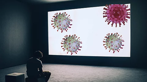 Image symbolizing the media aura about the Coronavirus, which ne gebeugt sitzender Mann vor einer Leinwand mit Coronaviren