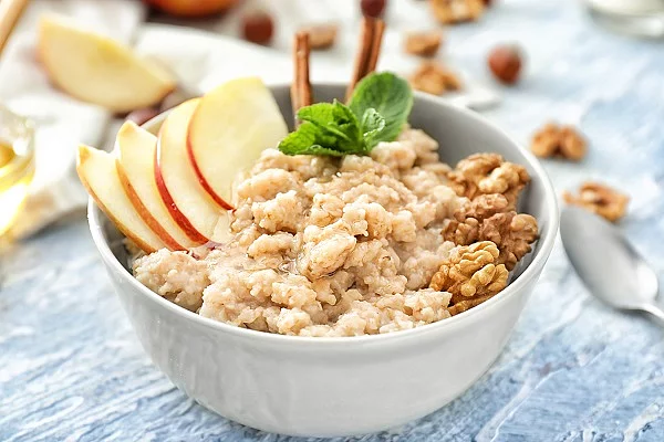 Tasty oatmeal with apple and walnut in bowl on table Porridge mit Apfel und Walnüssen