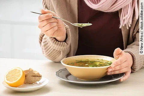 Frau isst eine Hühnersuppe.