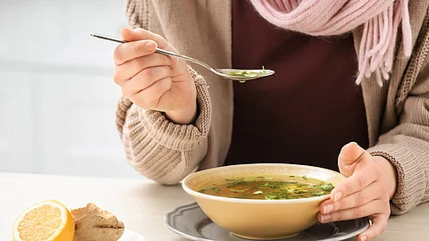 Frau isst eine Hühnersuppe.