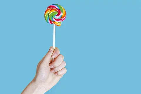 Hand hält bunten Lutscher in die Höhe