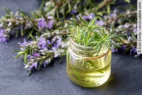 Rosmarin Öl Gefäß dekoriert mit Pflanze und Blüte.