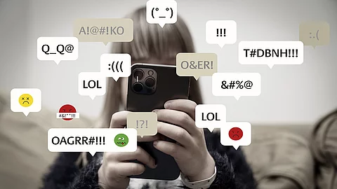 Mädchen schaut auf Smartphone, Sprechblasen mit Mobbingnachrichten