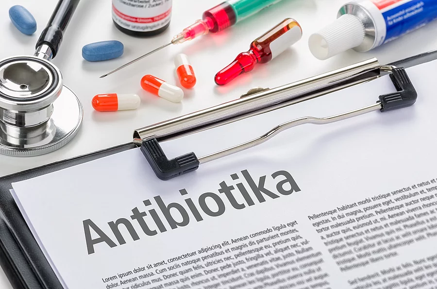 Antibiotika Klemmbock mit Zeitschriftenartikel: Überschrift Antibiotika, daneben Spritzen und Pillen