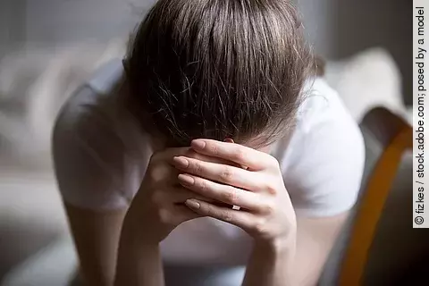 junge Frau mit den Händen vor dem Gesicht, traurig