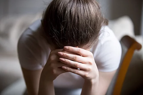 junge Frau mit den Händen vor dem Gesicht, traurig