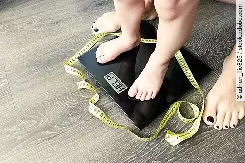 Kinderfüße auf einer Waage, die Waage zeigt: Help